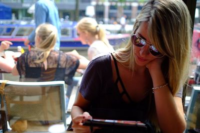 Young woman using digital tablet at table in restaurant