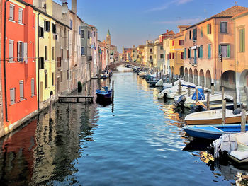 Boats moored in canal amidst buildings in city