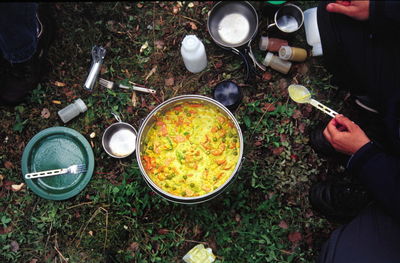 Cropped hands of man having food while sitting on field