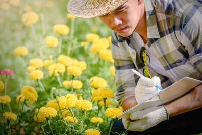 Midsection of man holding yellow flowering plants