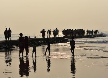 Silhouette people on beach against clear sky