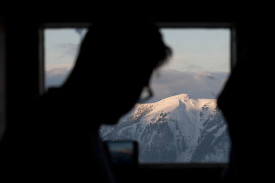 Portrait of silhouette man against sky seen through window