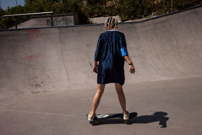 Rear view of woman skateboarding at skateboard park