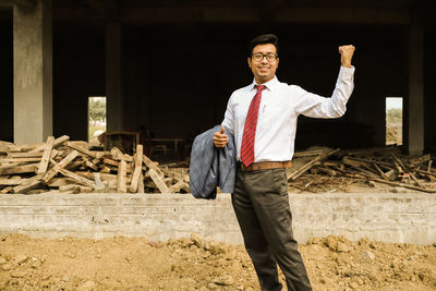 Portrait of a smiling young man standing at construction site