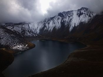 Scenic view of lake by snowcapped mountains against sky