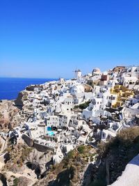 Aerial view of townscape by sea against clear blue sky