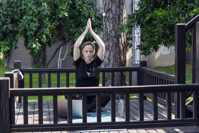 Portrait of young woman standing against railing