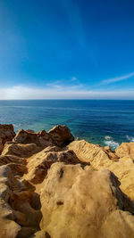 Rocks on beach against blue sky