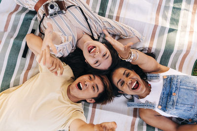 Friends screaming while relaxing on picnic blanket