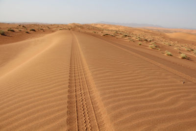 High angle view of tire tracks in desert against sky