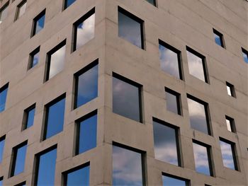 The facade of a modern building in essen with a lot of windows, reflecting the sky and clouds. 