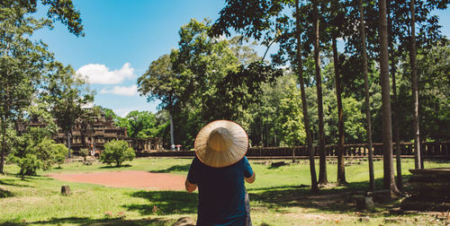 Rear view of man in hat standing against trees