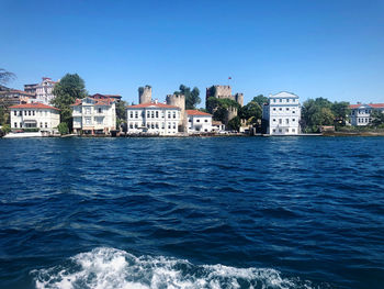 Sea by buildings against clear blue sky