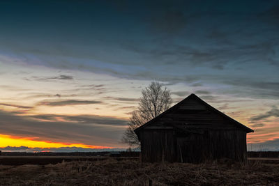 House on field against sky during sunset