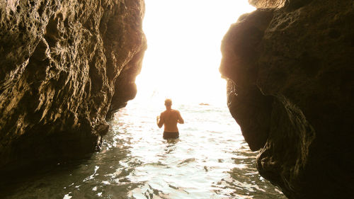 Rear view of woman on rocks by sea