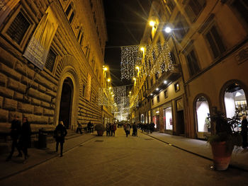 People on street below illuminated lighting decoration in city at night