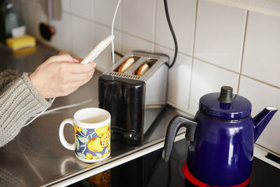 Hands holding cell phone over kitchen worktop