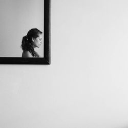 Woman reflecting in mirror on wall