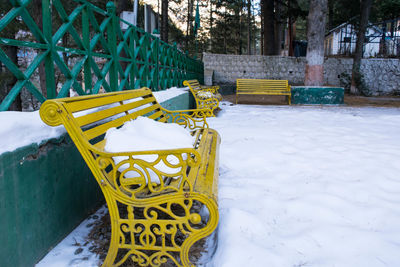 Empty bench on snow covered field