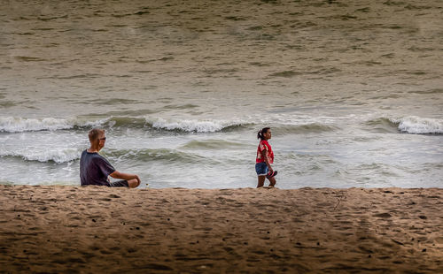 Rear view of friends enjoying at beach