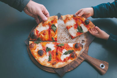 High angle view of hand holding pizza