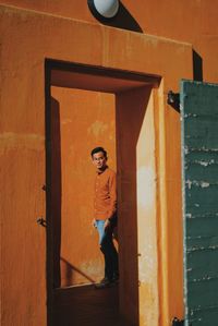 Full length of man standing by wall seen through doorway