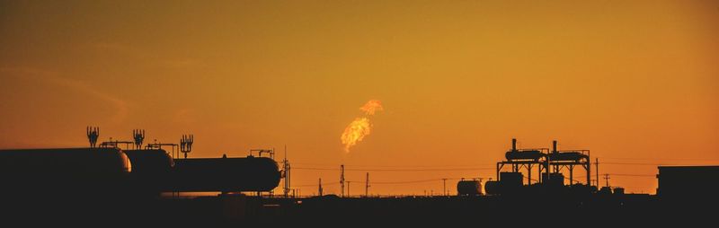 Silhouette smoke emitting from factory against sky during sunset