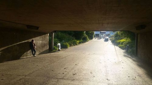 Rear view of people walking on road in tunnel