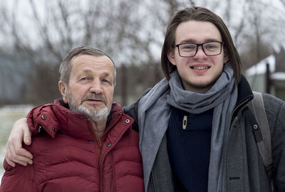 Portrait of smiling grandfather and grandson standing outdoors