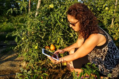 Side view of woman using mobile phone by plant