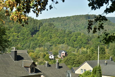 Houses by trees and mountains against sky