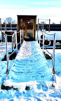 Empty chairs by swimming pool against sky during winter