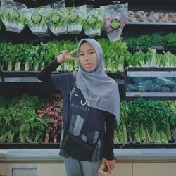 Portrait of smiling young woman standing against plants