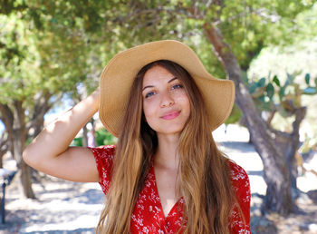 Portrait of smiling young woman wearing hat while standing on land