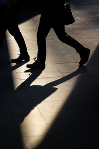 Low section of silhouette people on tiled floor