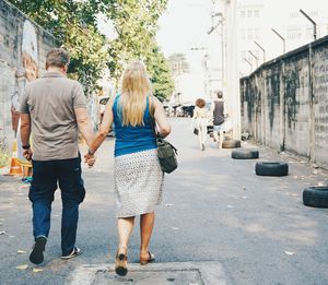 Rear view of couple holding hands while walking on street
