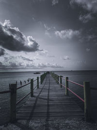 Wooden pier over sea against sky