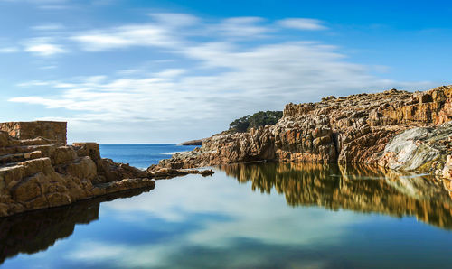 Rock formations by sea against sky