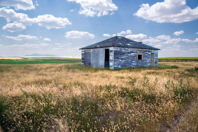 Abandoned house on field against sky