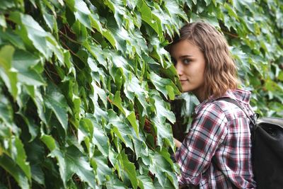 Portrait of young woman standing against plants