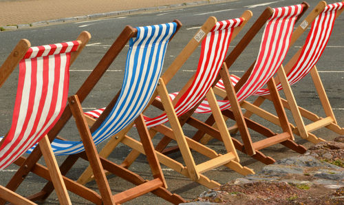 Deck chairs on road during sunny day