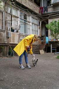 Young photographer girl playing with cat on the street in old city