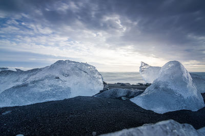 Ice at beach against sky during sunset