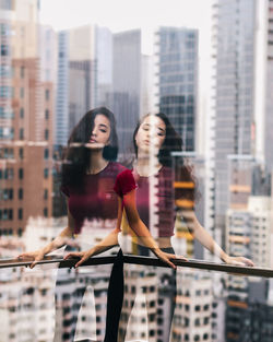Portrait of young woman standing against skyscrapers in city