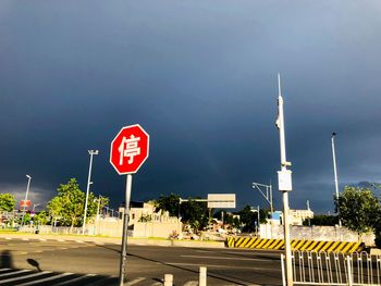 Road sign by street against sky in city