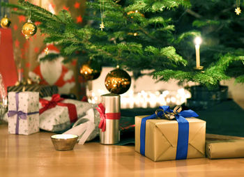 Close-up of gift boxes by christmas tree at home