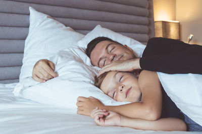 Father with son sleeping on bed at home
