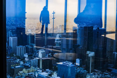 Modern buildings in city against sky seen through glass