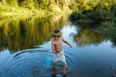 Rear view of shirtless man standing in lake