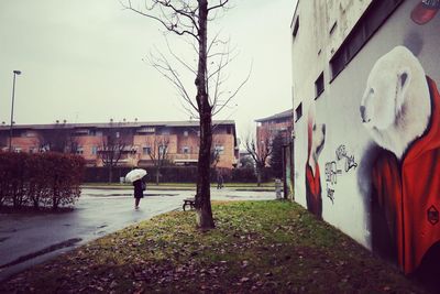 Man with umbrella in city against sky